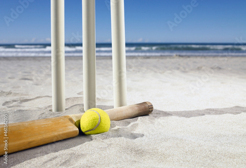 Bat and ball laying beside cricket stumps at the beach photo