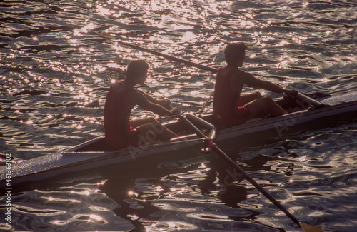 Two men rowing in double scull on water photo