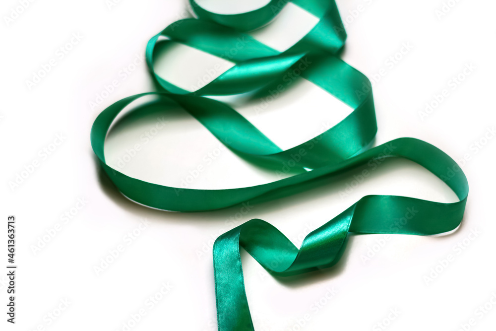 Defocus close-up Christmas tree made of green ribbon on white background. Minimal Christmas holiday background of curly tape. Xmas decor flat lay. Out of focus. Defocus close-up Christmas tree made of green ribbon on white background. Minimal Christmas holiday background of curly tape. Xmas decor flat lay. Out of focus.