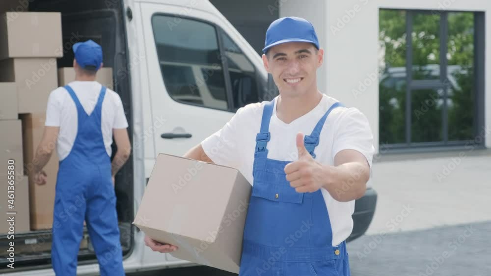 Two young workers of removal company are loading boxes and furniture into a minibus Two young workers of removal company are loading boxes and furniture into a minibus