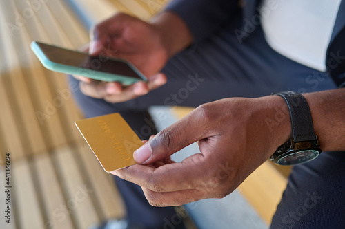 Close up picture of a man holding a credit card and a smartphone