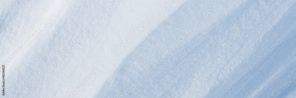 Beautiful winter background with snowy ground. Natural snow texture. Wind sculpted patterns on snow surface. Wide panoramic texture for background and design.