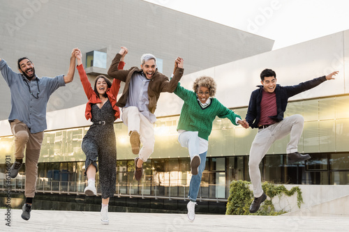 Young diverse people jumping outdoor in the city - Multiracial friends having fun together - Soft focus on center man face