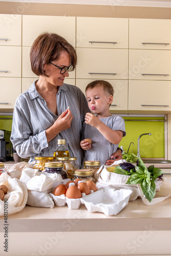 Adult mother feeds her son with nuts in the kitchen. photo