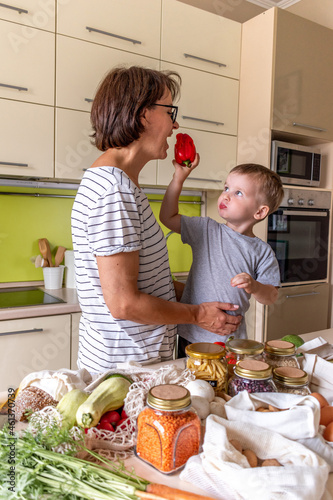 Son feeds his mom with sweet pepper. Vegetarian food. Communication of a mother with a child at home. photo