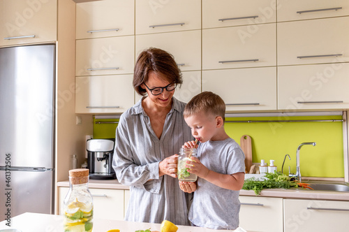 Adult woman is drinking lemonade with her son. Refreshing drink. Summer heat.