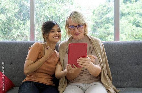 Fototapeta Asian daughter take a selfie with her adopted caucasian mother through a tablet computer