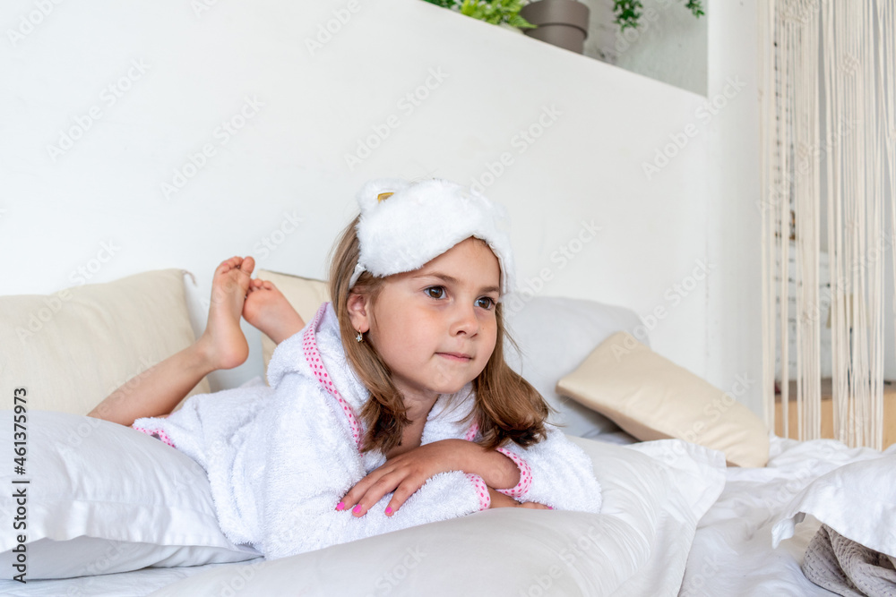 Daughter are dressed in white terry robes, lie on the bed. Nursing communication in the family. Daughter are dressed in white terry robes, lie on the bed. Nursing communication in the family.