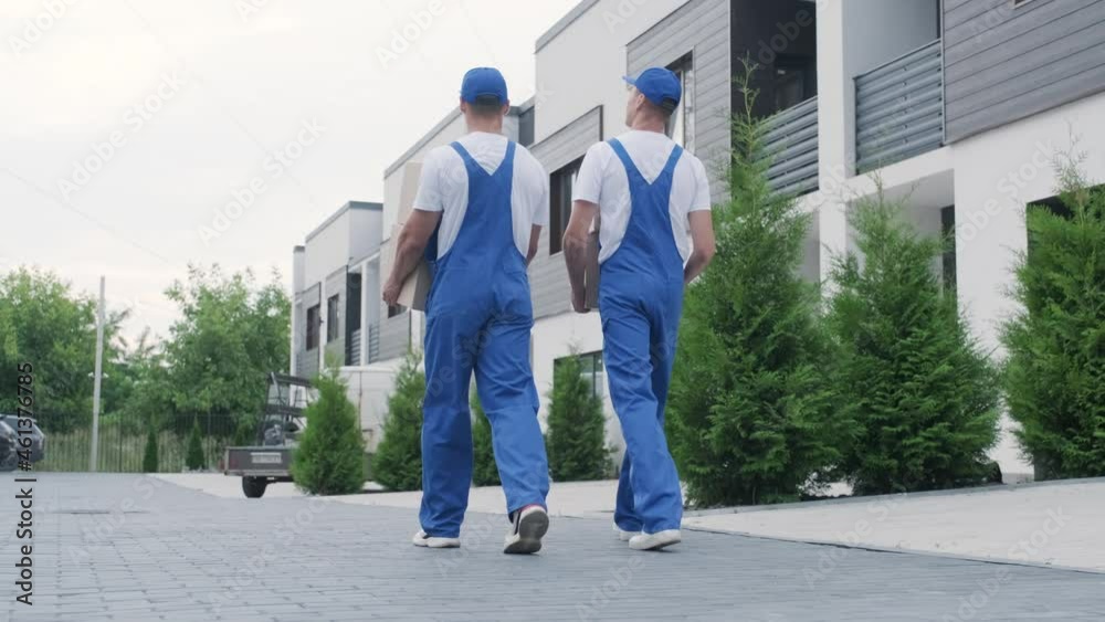 Two young workers of removal company deliver boxes to a customer's home Two young workers of removal company deliver boxes to a customer's home