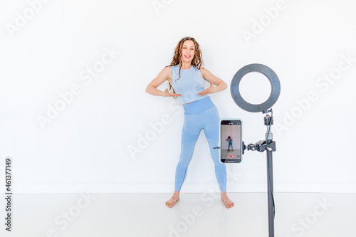 Young diverse woman is recording a dance instructional video on her phone. Copy space
