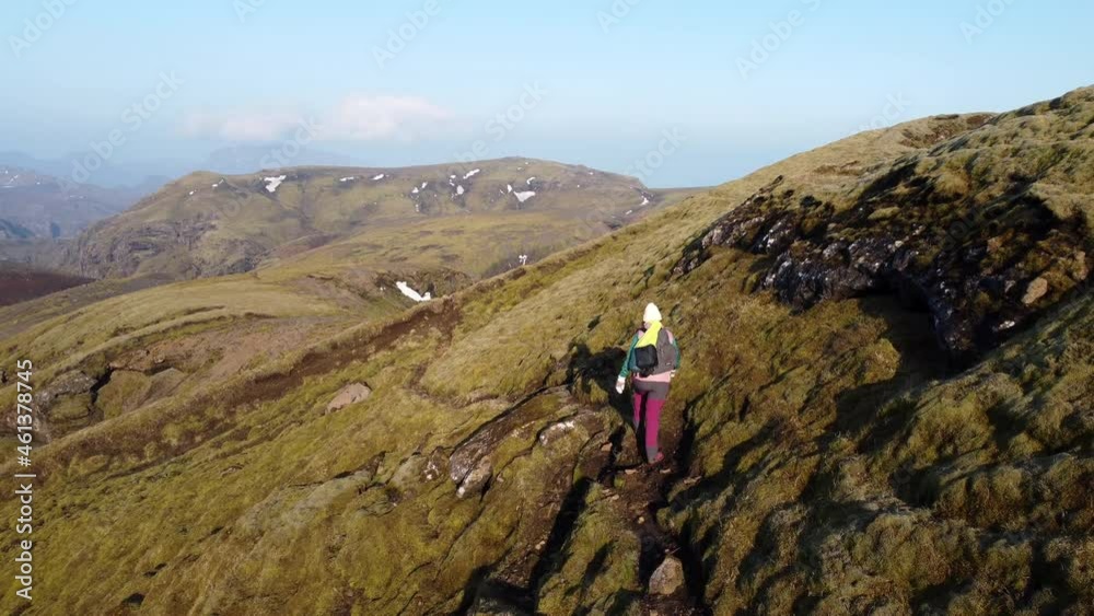Colourful hiker walking on the narrow muddy mountain patch curved out from delicate greenish moss Colourful hiker walking on the narrow muddy mountain patch curved out from delicate greenish moss