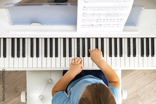 Cute baby boy playing white electrical forte piano pressing keys kid studying at musical school photo