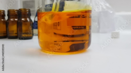 Shaking a sample of rosehip oil in a beaker in the laboratory photo