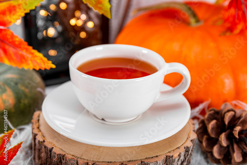  A cup of tea with lemon, autumn leaves and pumpkin close up. The concept of a cozy autumn at home.