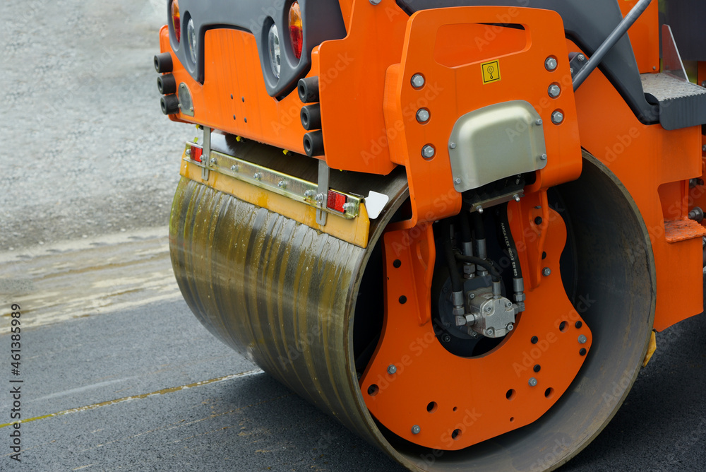 An orange road roller is grinding the road during the day.
