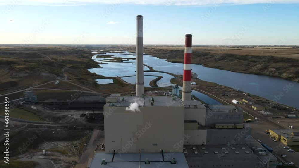 Aerial 4k time lapse of power plant with two high cooling towers next to large blue river in north america. Smoke coming out of chimney moving in the wind.