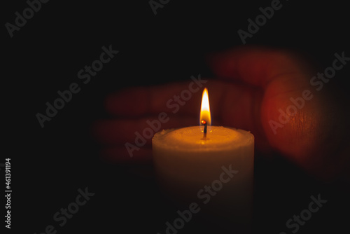 One palm take care of candle fire at night.Selective focus,Dark black background.Closeup.