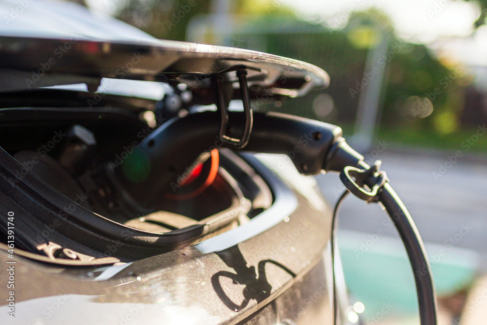 Charging an electric car with the power cable supply plugged in.Charging modern electric car on the street which are the future of the automobile Charging an electric car with the power cable supply plugged in.Charging modern electric car on the street which are the future of the automobile