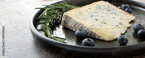 ceramic dish with gorgonzola cheese, rosemary and blueberries on the table photo