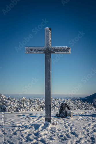 Mountain cross for hikers, Western Tatras, Poland. Tall wooden christian sign, snow on a peak, winter in the mountains. Selective focus on the structure, blurred background.