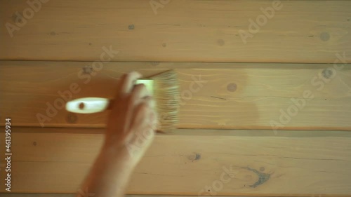 Close up of man hand painting exterior wooden wall of a house, painter working on his job