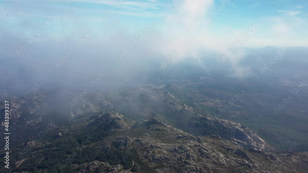 View from above, flying above the clouds, stunning aerial view of a granitic massif surrounded by moving clouds during a sunny day. Mount Limbara (Monte Limbara) Sardinia, Italy.