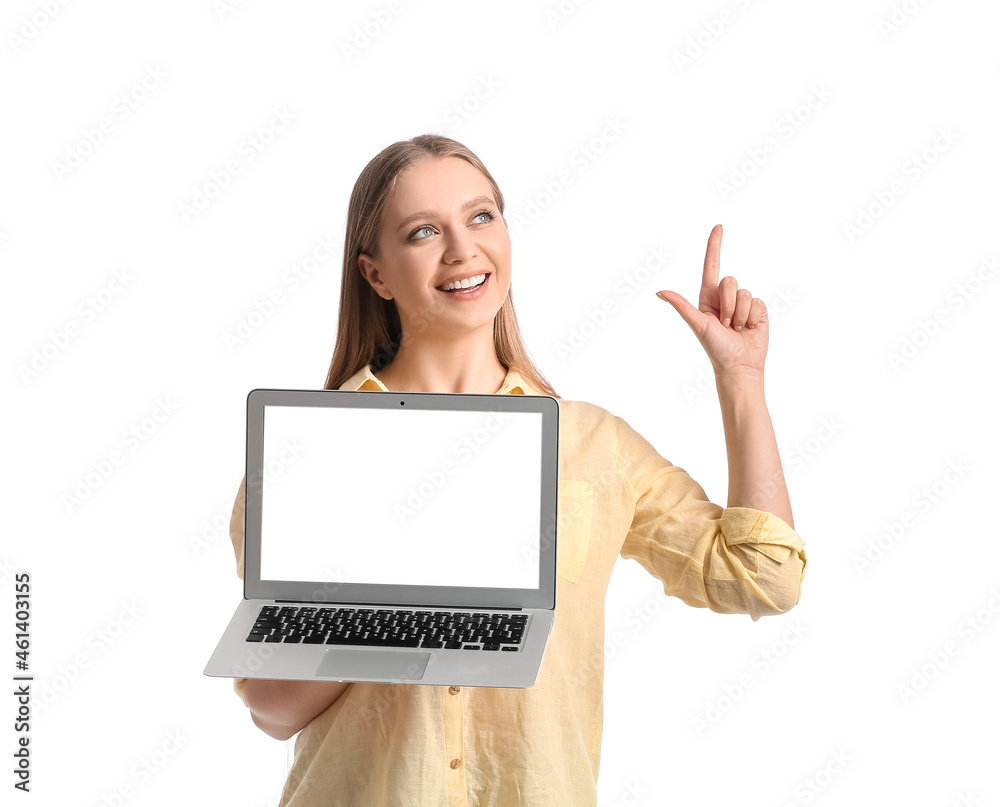 Beautiful young woman holding laptop with blank screen and pointing at something on white background Beautiful young woman holding laptop with blank screen and pointing at something on white background