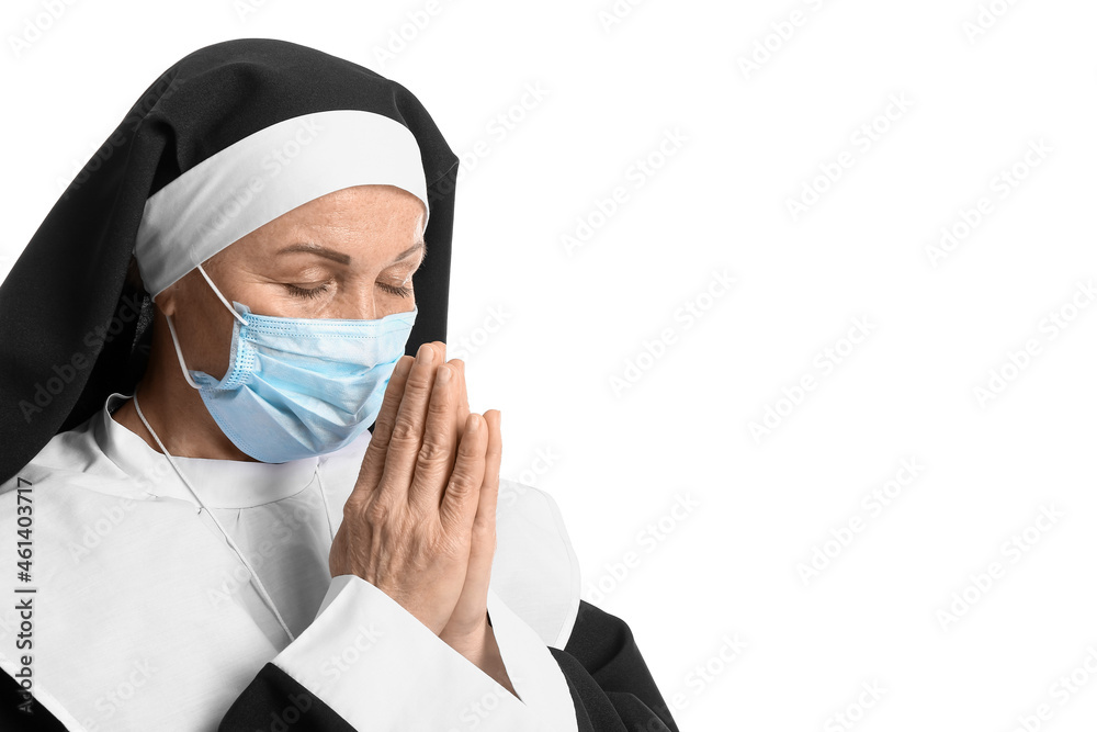 Mature nun in medical mask praying on white background Mature nun in medical mask praying on white background