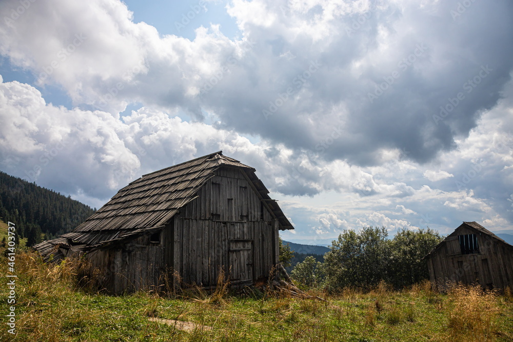 Abandoned buildings in the mountains, wooden houses against the background of rocks, the natural landscape, green meadows and forests Abandoned buildings in the mountains, wooden houses against the background of rocks, the natural landscape, green meadows and forests