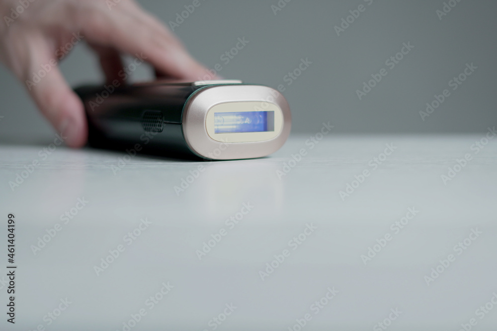 Man's hand holding a professional portable laser hair removal. The portable device provides professional hair removal at home comfort.