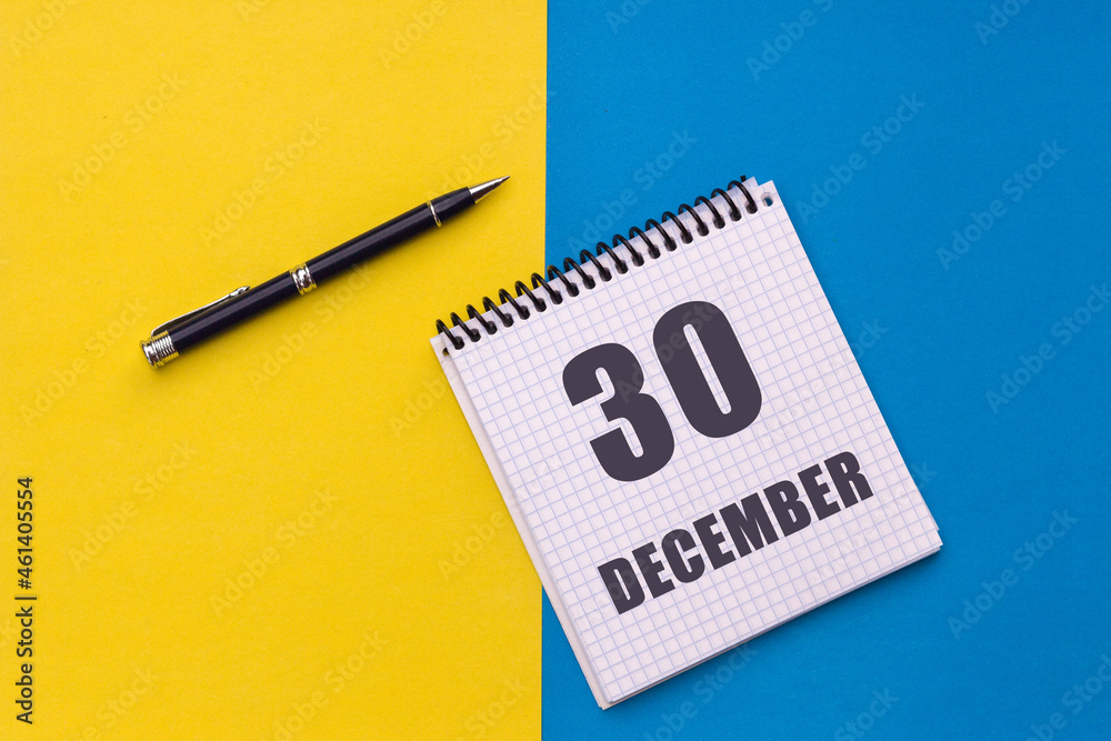 December 30th. Day 30 of month, calendar date. Notebook with a spiral and pen lies on a yellow-blue background December 30th. Day 30 of month, calendar date. Notebook with a spiral and pen lies on a yellow-blue background