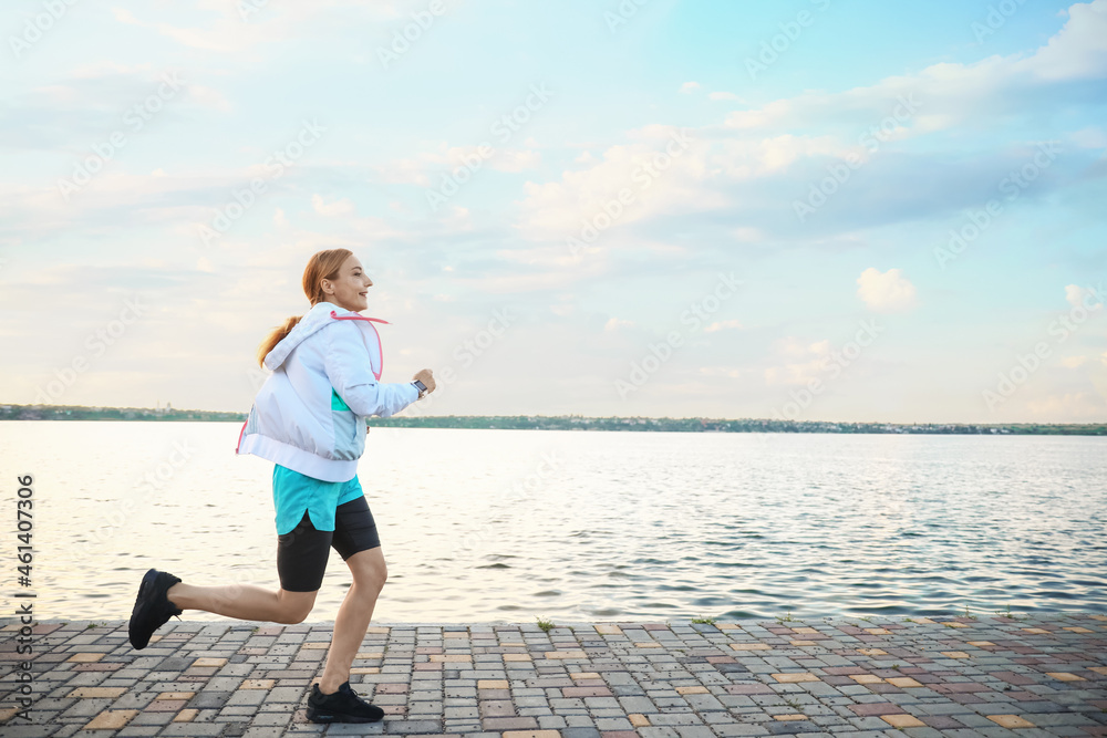 Sporty mature woman running near river