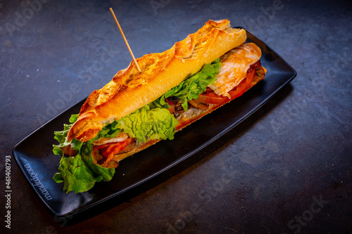 Vegetarian sandwich with chicken on a black background, on a white plate