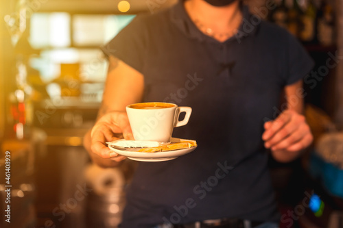 A waitress with a white cup of decaf coffee handing it to a customer