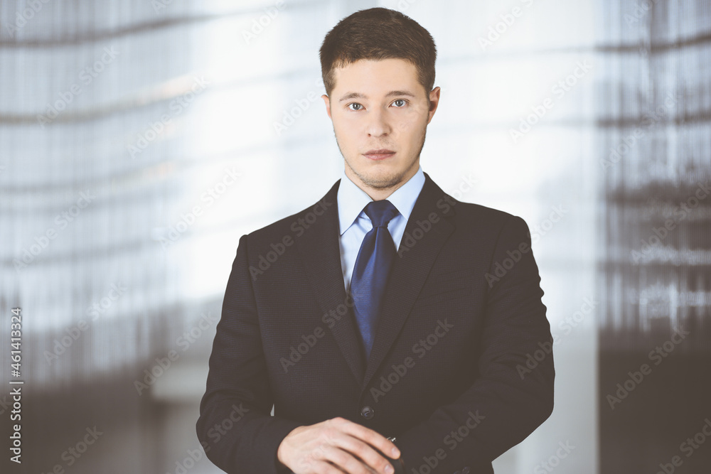 Young businessman wearing suit and tie, while standing in the office. Business success concept nowadays Young businessman wearing suit and tie, while standing in the office. Business success concept nowadays