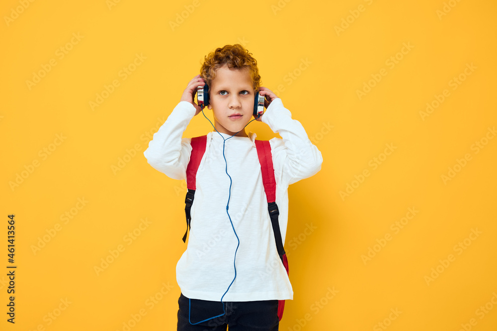 schoolboy with headphones music Red backpack yellow background schoolboy with headphones music Red backpack yellow background