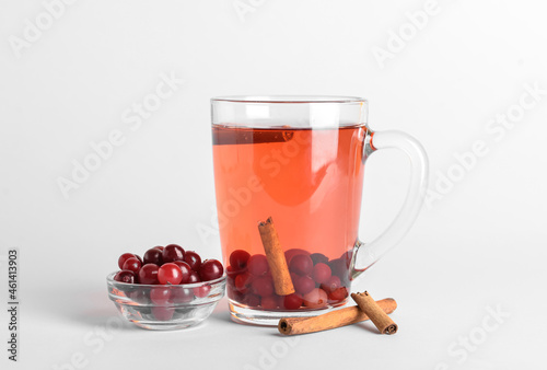 Glass cup of tasty cranberry tea with cinnamon on white background