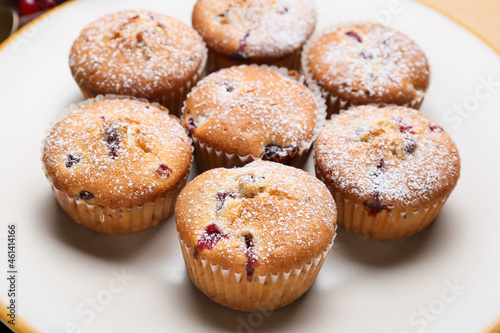 Plate with tasty cranberry muffins on table, closeup