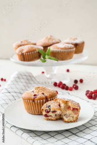 Plate with tasty cranberry muffins on table