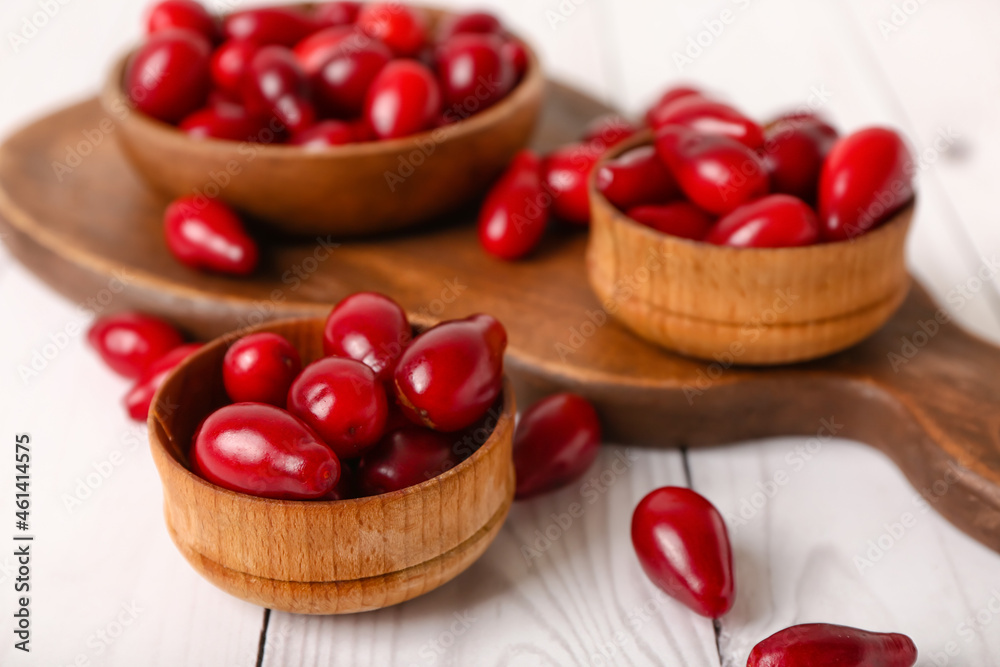 Bowls with ripe dogwood berries on light wooden background, closeup Bowls with ripe dogwood berries on light wooden background, closeup