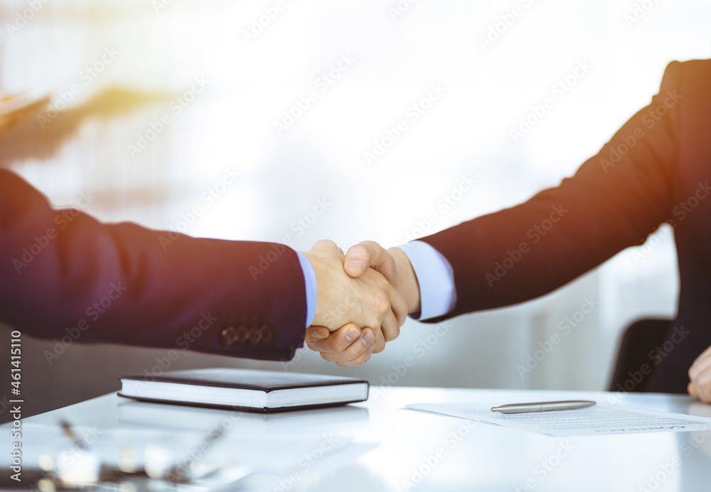 Business people shaking hands at meeting or negotiation, close-up. Group of unknown businessmen in a sunny modern office. Teamwork, partnership and handshake concept