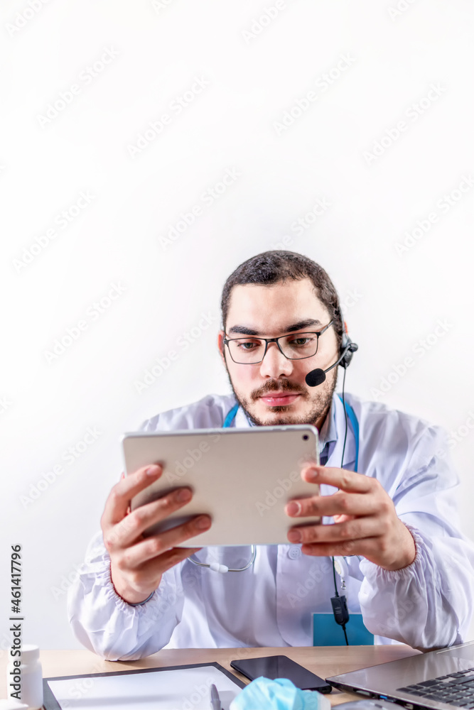Male doctor using digital tablet. Physician sitting behind a desk