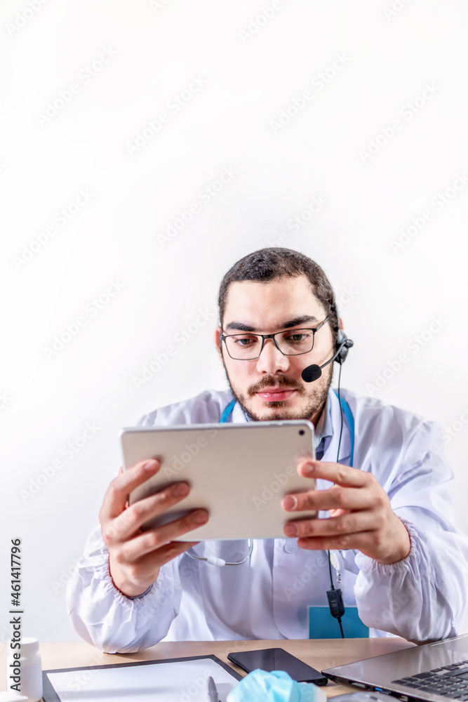 Male doctor using digital tablet. Physician sitting behind a desk Male doctor using digital tablet. Physician sitting behind a desk