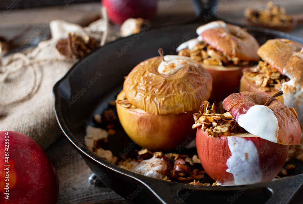 Breakfast for autumn and winter with baked apple filled with granola and topped with yogurt and cinnamon