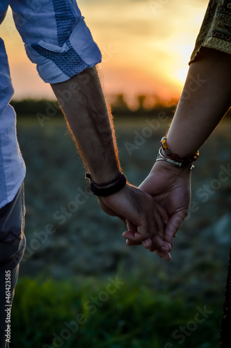 Couple of lovers hands holding romantically at sunset in the countryside, close up