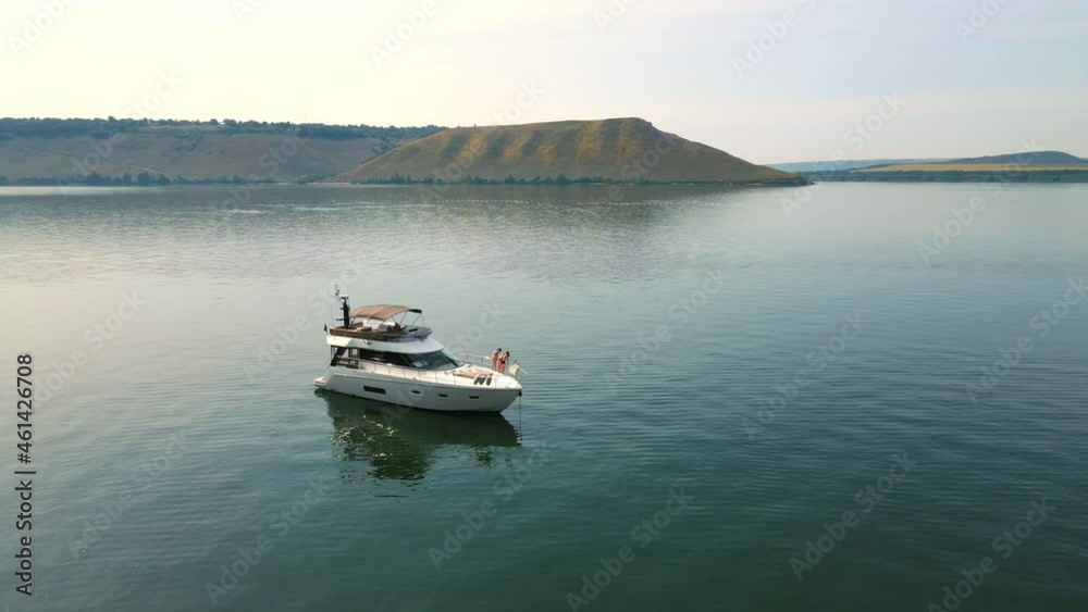 Aerial Shot Luxurious yachts near the rocky shore. Flight around a boat standing near the shore. A tourist boat stands near a rock in a sea bay. Aerial Shot Luxurious yachts near the rocky shore. Flight around a boat standing near the shore. A tourist boat stands near a rock in a sea bay.