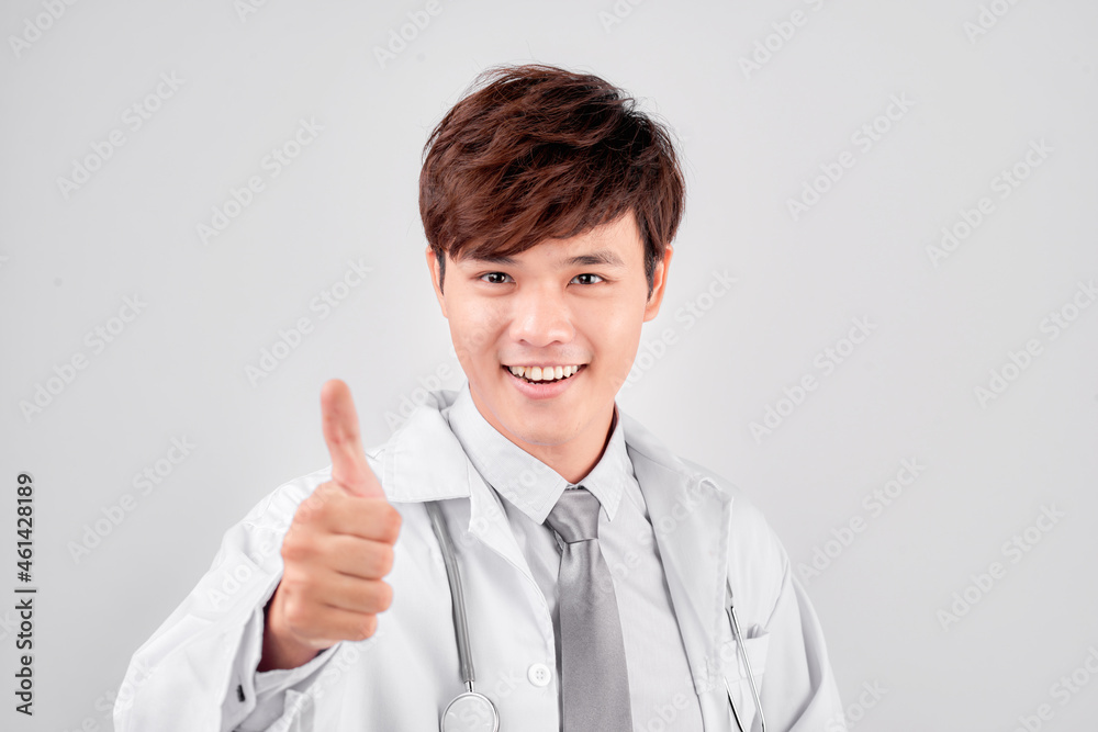 Positive asian male doctor in lab coat showing thumb up gesture over white background Positive asian male doctor in lab coat showing thumb up gesture over white background
