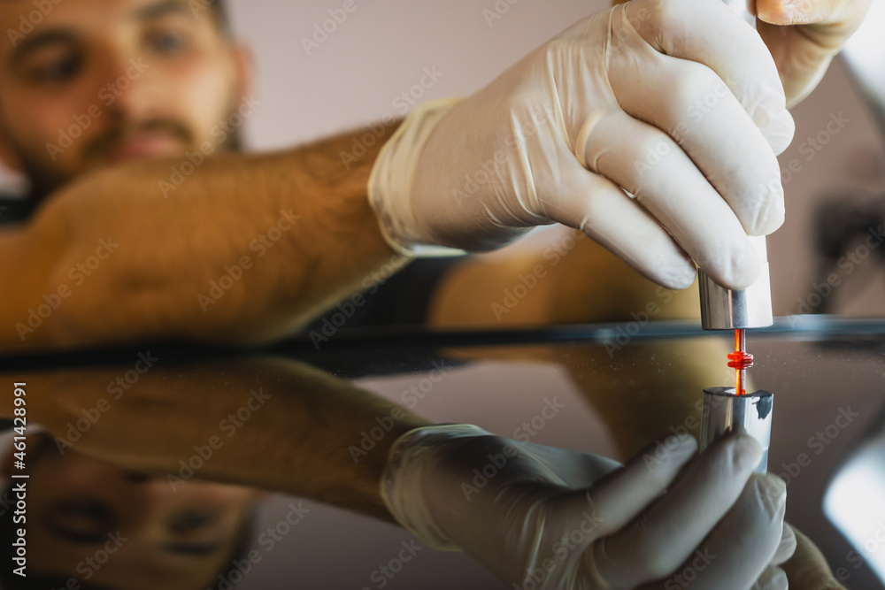 Photo of a process dent removing without paint, young professional worker makes dent repair on the car roof in the service.