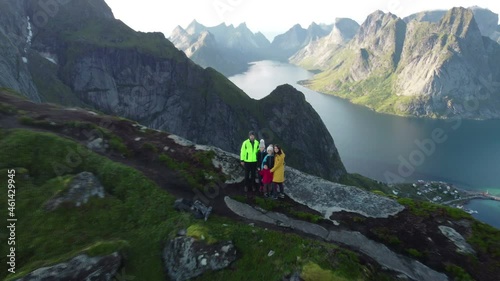 Happy family on top of the mountains and looking down on Reine after climbing Reinebringen treeking path with lots of stairs, Lofoten, northern Norway