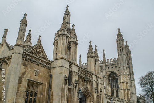 Facade of Gothic style edifice next to a Gothic style Chapel with ornate stained glass windows in Cambridge England